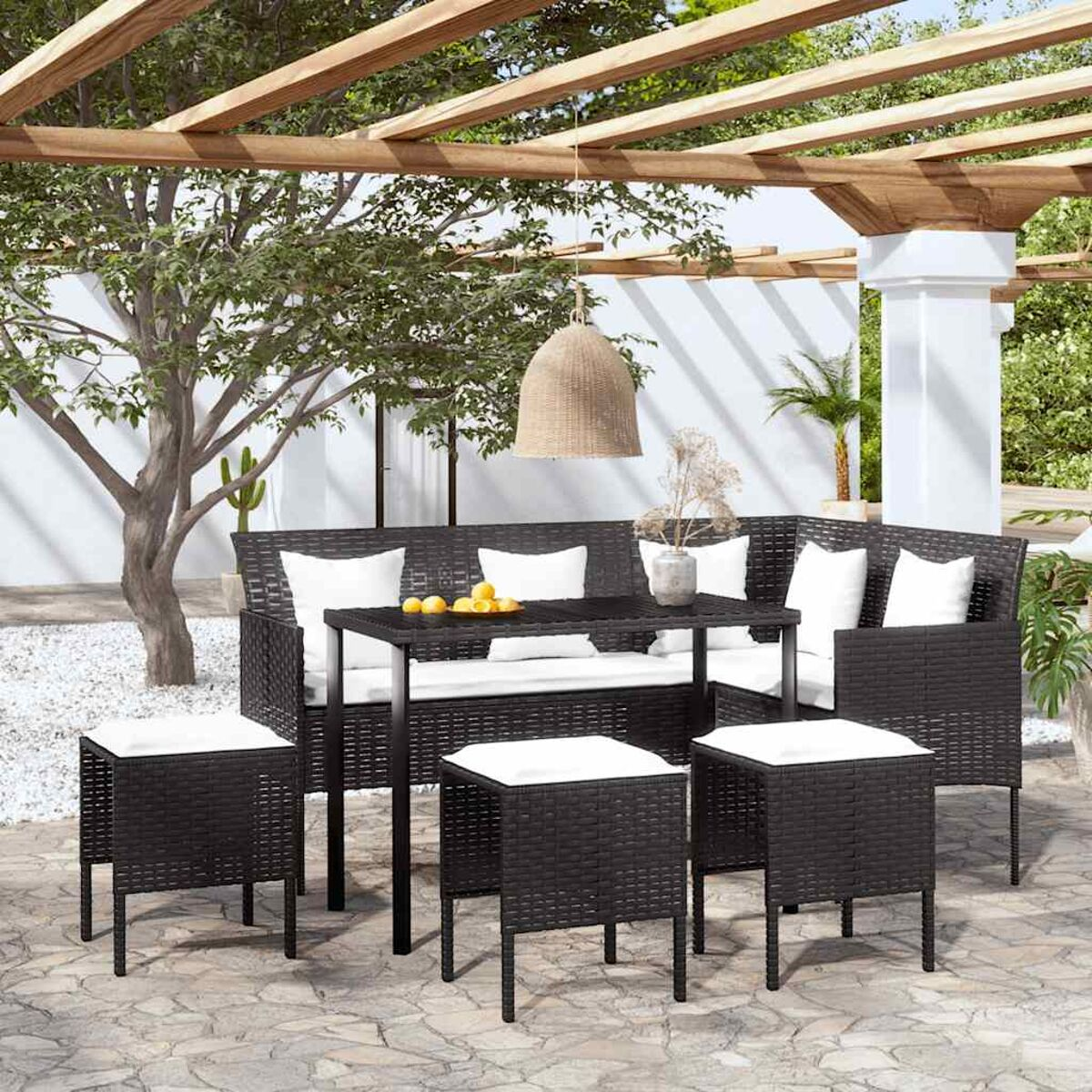 Essgruppe im Freien mit schwarzen Möbeln, weißen Kissen und Pergola.