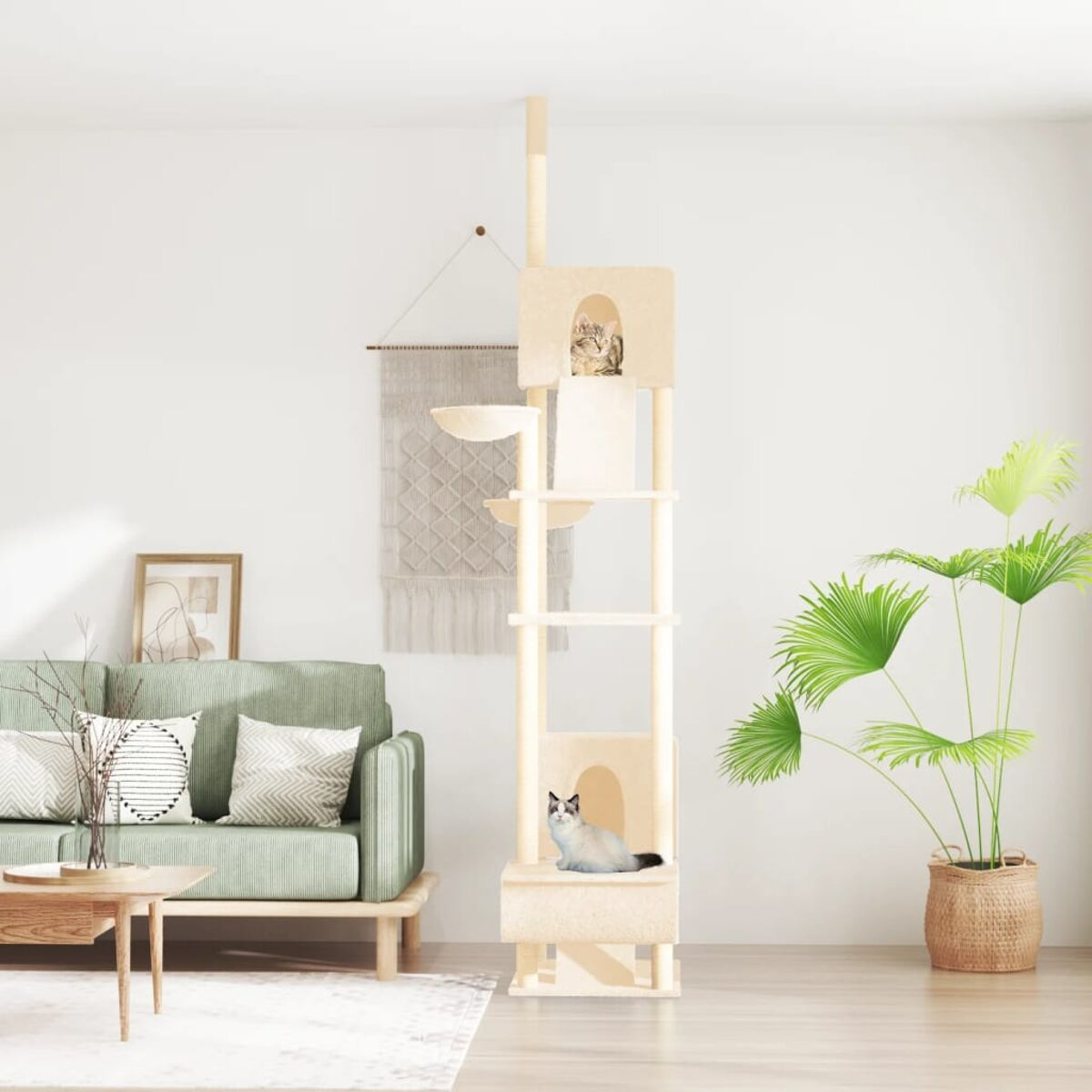 Ein Katzenbaum mit zwei Katzen, einem Sofa und einer Pflanze. Der Katzenbaum steht vor einer Wand mit einem Wandteppich.