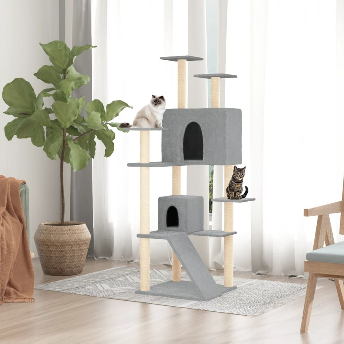 Ein mehrstöckiger Katzenbaum mit zwei Katzen. Er hat Plattformen, ein Haus und eine Rampe. Vor einem Fenster.