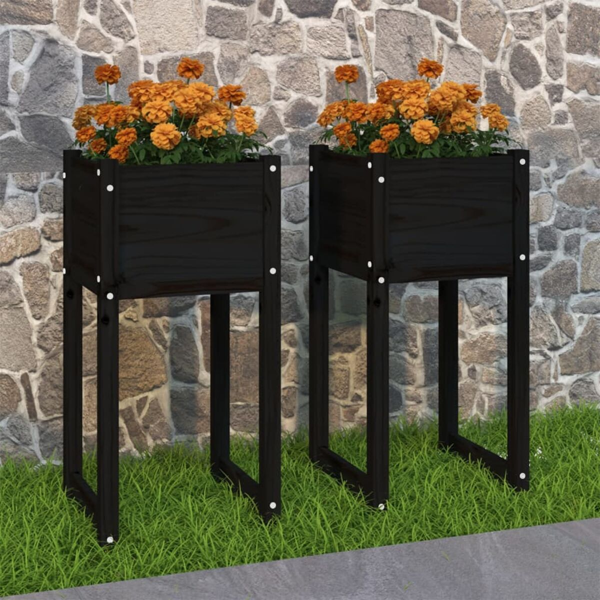 Zwei schwarze Holzpflanzer mit orangefarbenen Blumen, auf Gras platziert, vor einer Steinmauer.