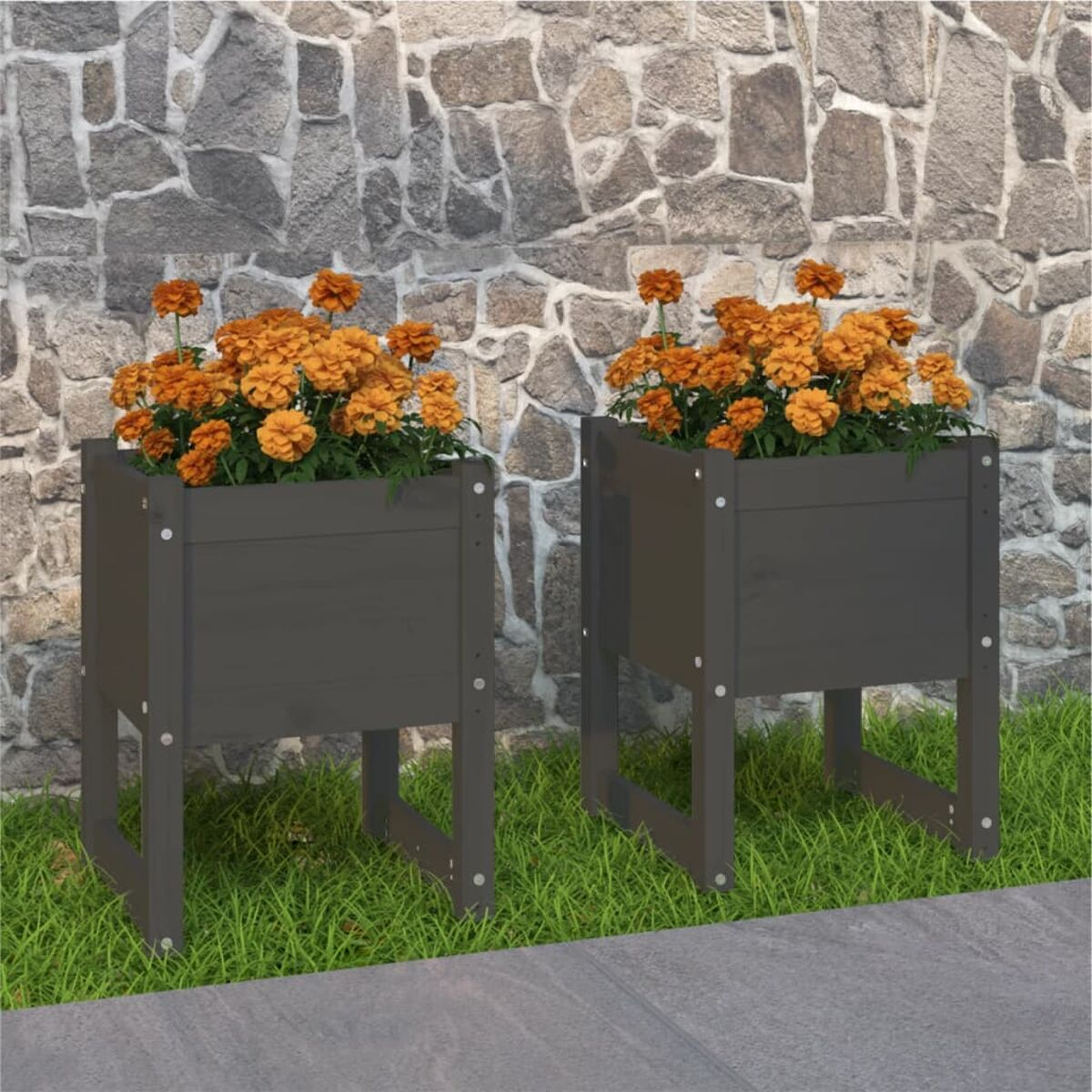 Zwei dunkelgraue Holzpflanzgefäße mit orangefarbenen Blumen. Sie stehen auf Gras neben einer Steinmauer.