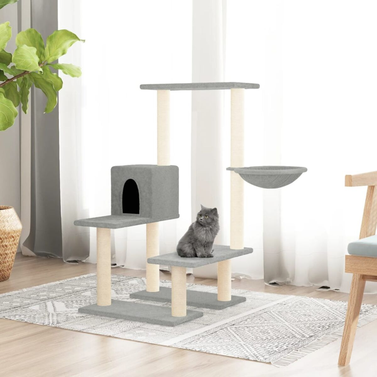 Katze sitzt auf einem grauen Katzenturm mit grauem Bett und Schüssel, weißer Hintergrund.