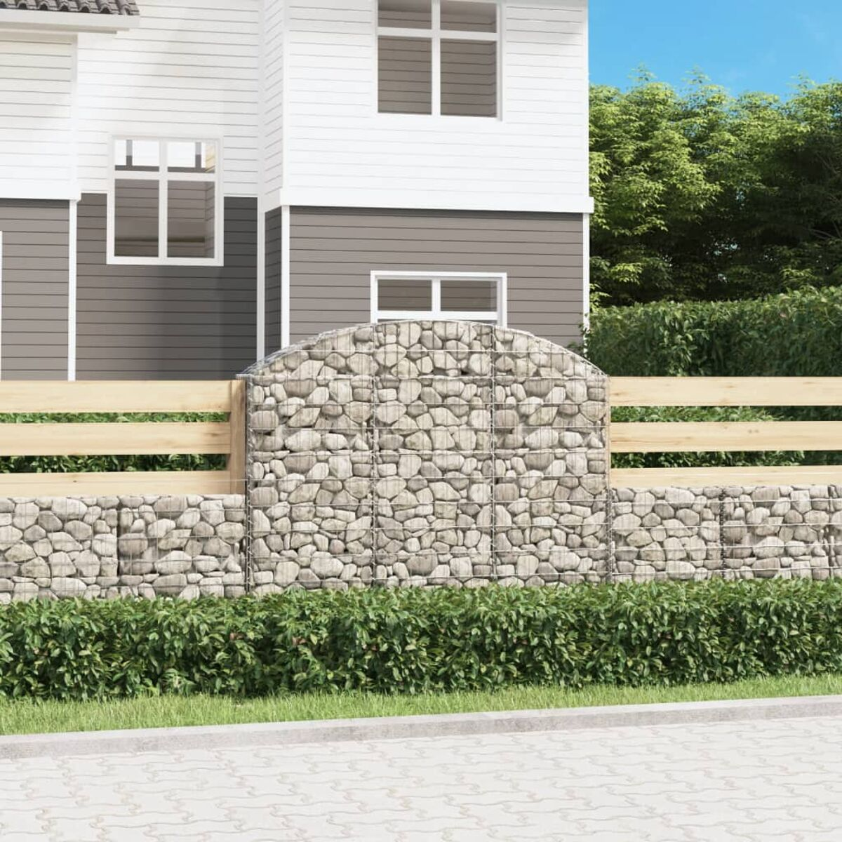 Steinmauer mit Holzzaun und Haus im Hintergrund.