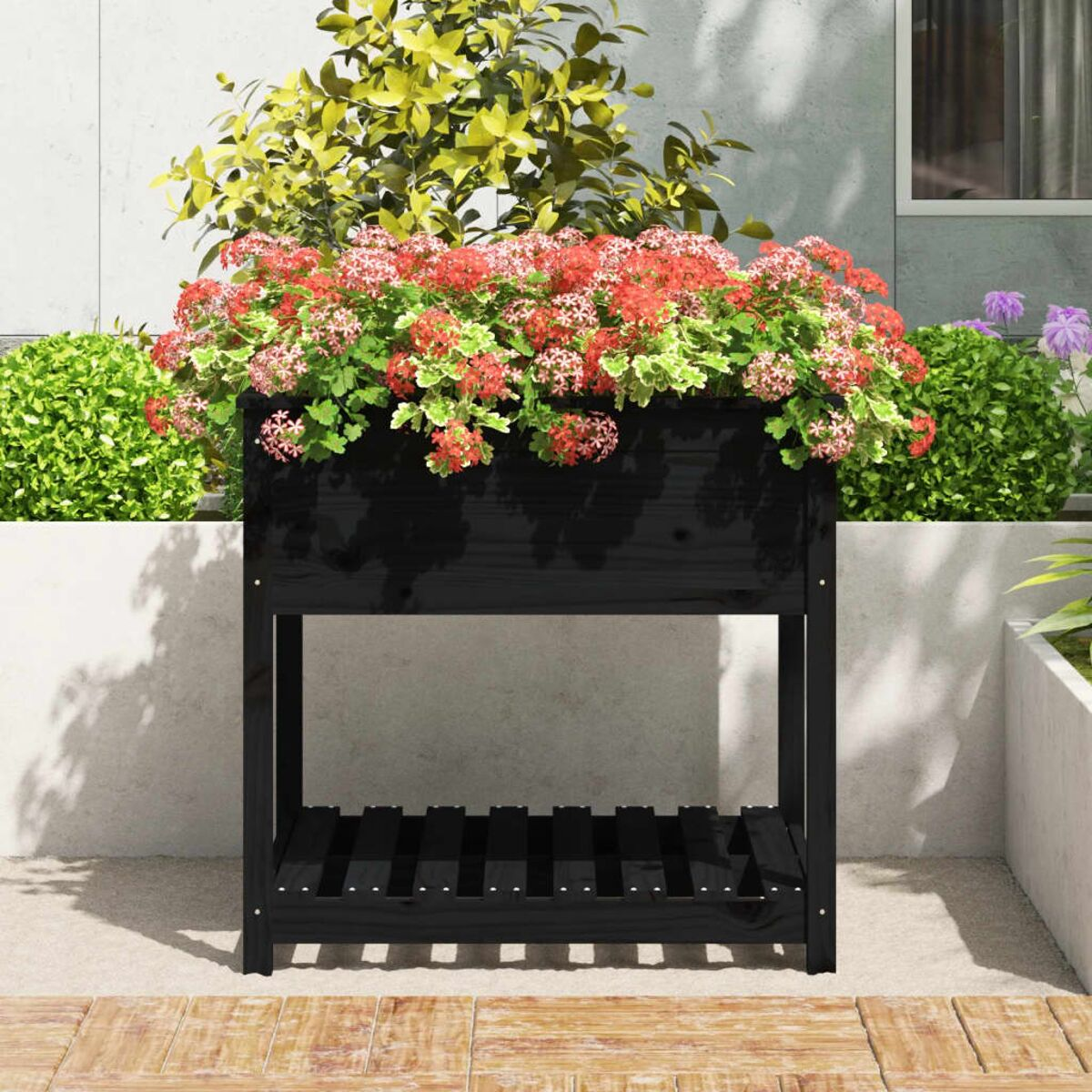 Schwarzer hölzerner Pflanzkasten, voller roter und grüner Blumen, auf einer Terrasse.