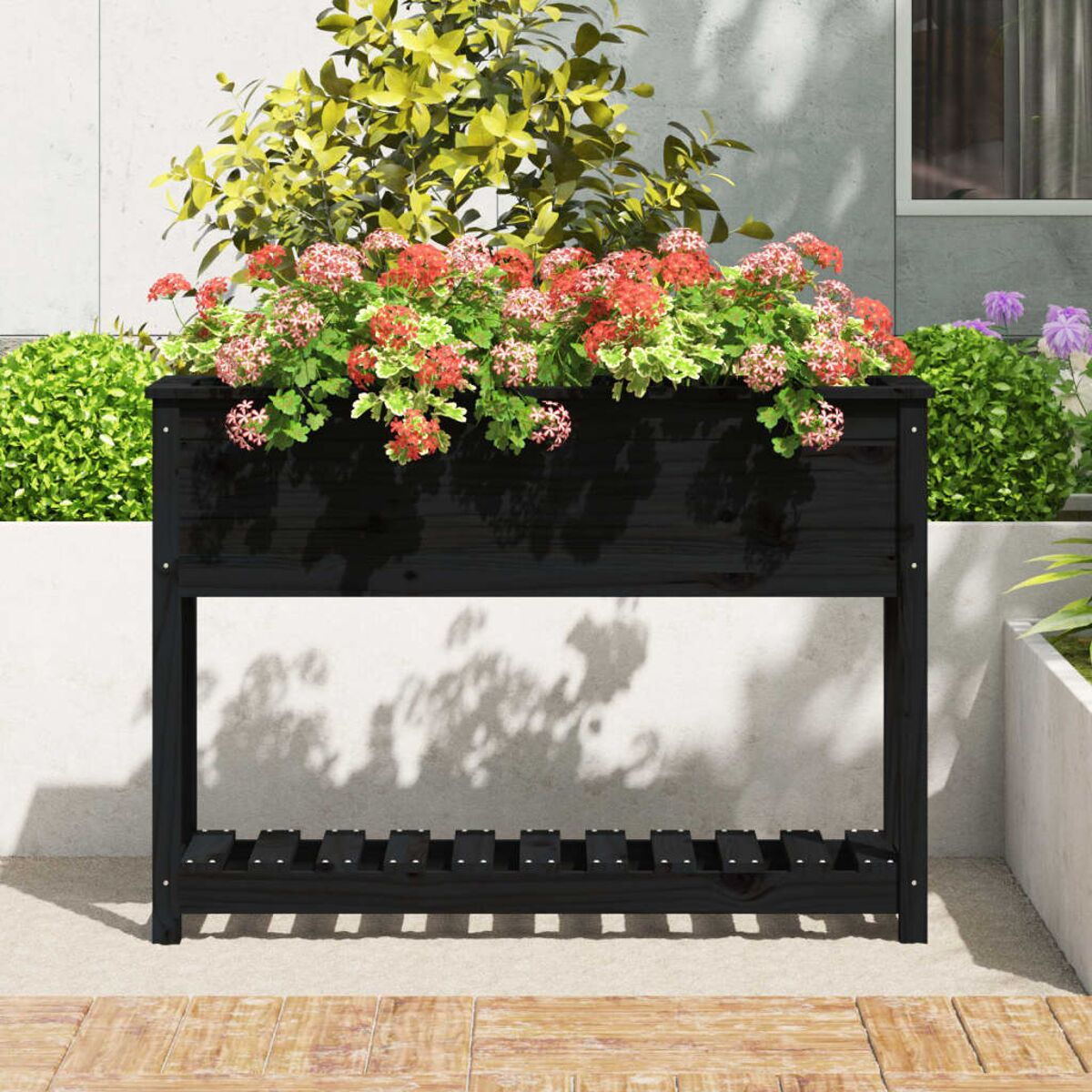 Schwarze Holzpflanzkasten mit Blumen, auf einer Terrasse mit weißem Wandhintergrund.