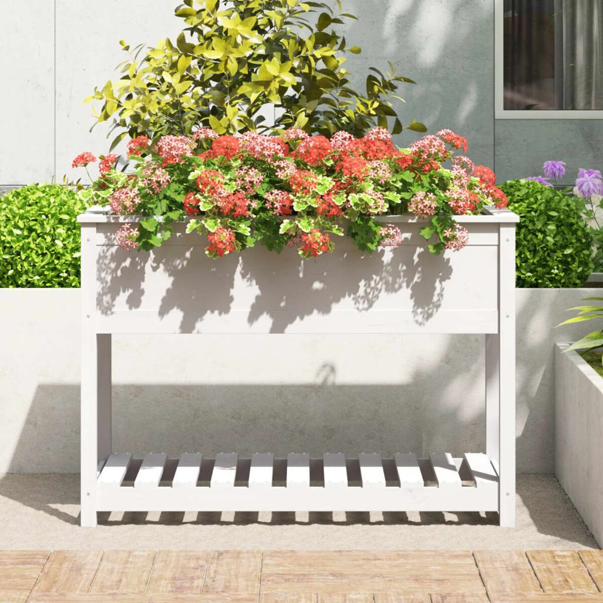 Eine weiße rechteckige Pflanzkasten mit roten und rosa Blumen gefüllt.