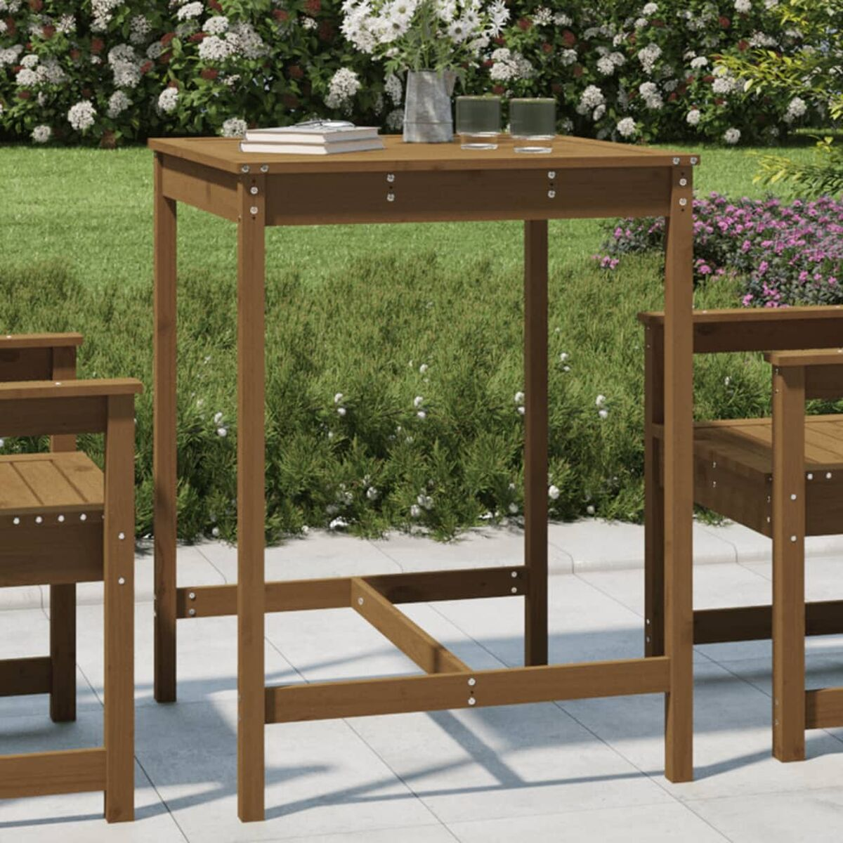 Hölzerner Bartisch im Freien mit quadratischer Platte, vor grünem Hintergrund mit Pflanzen und Blumen.