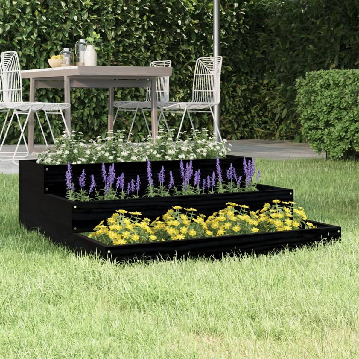 Ein gestufter Pflanzkübel mit verschiedenen Blumen in einem Garten.