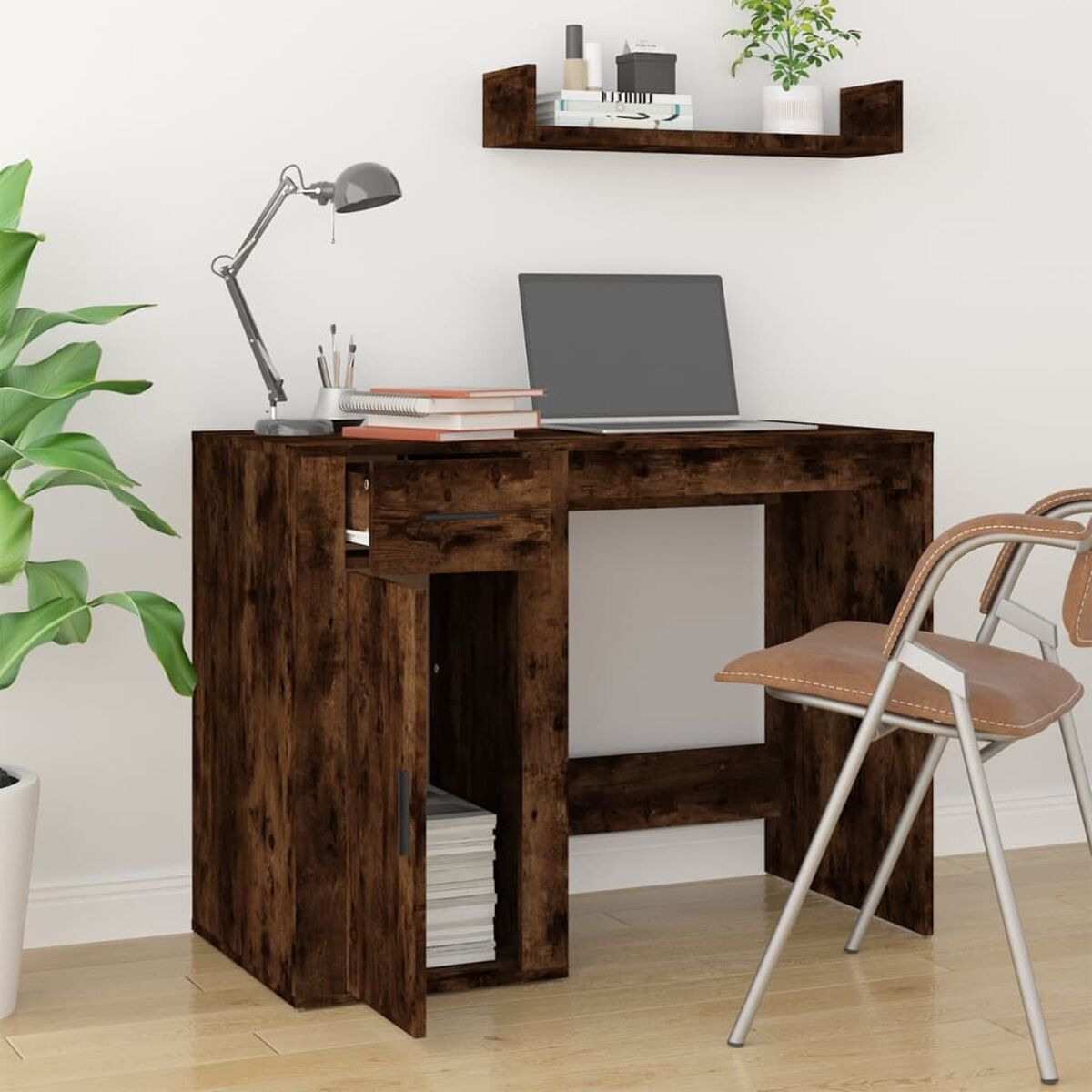 Ein brauner Holzschreibtisch mit Laptop, Lampe und Stuhl. Hintergrund: weiße Wand.