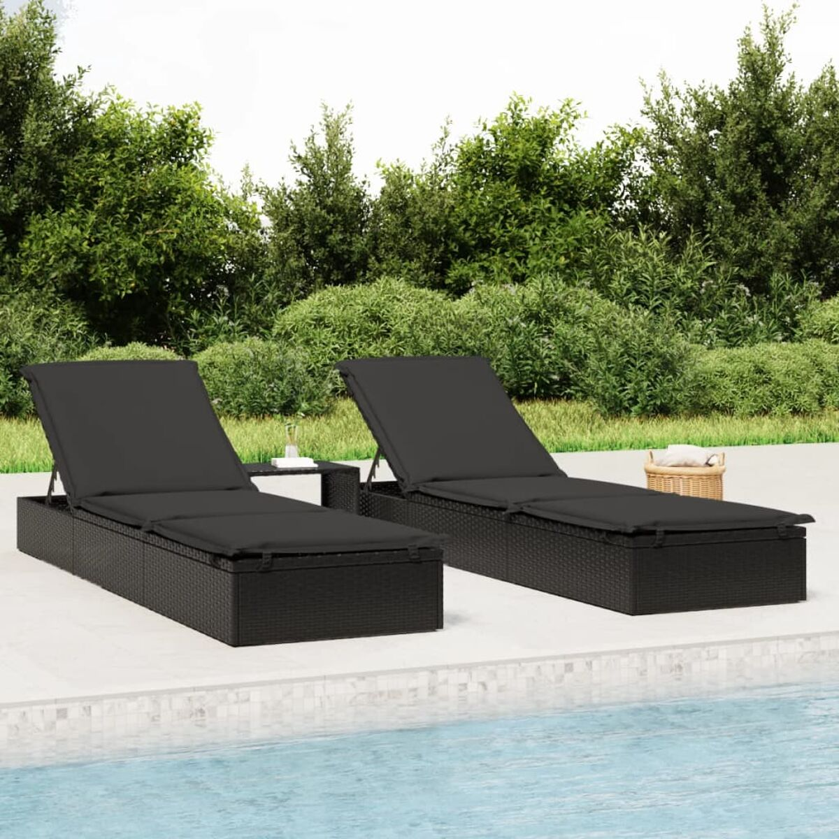 Zwei schwarze Liegestühle an einem Pool, mit einem kleinen Tisch und einem Korb mit Handtüchern.