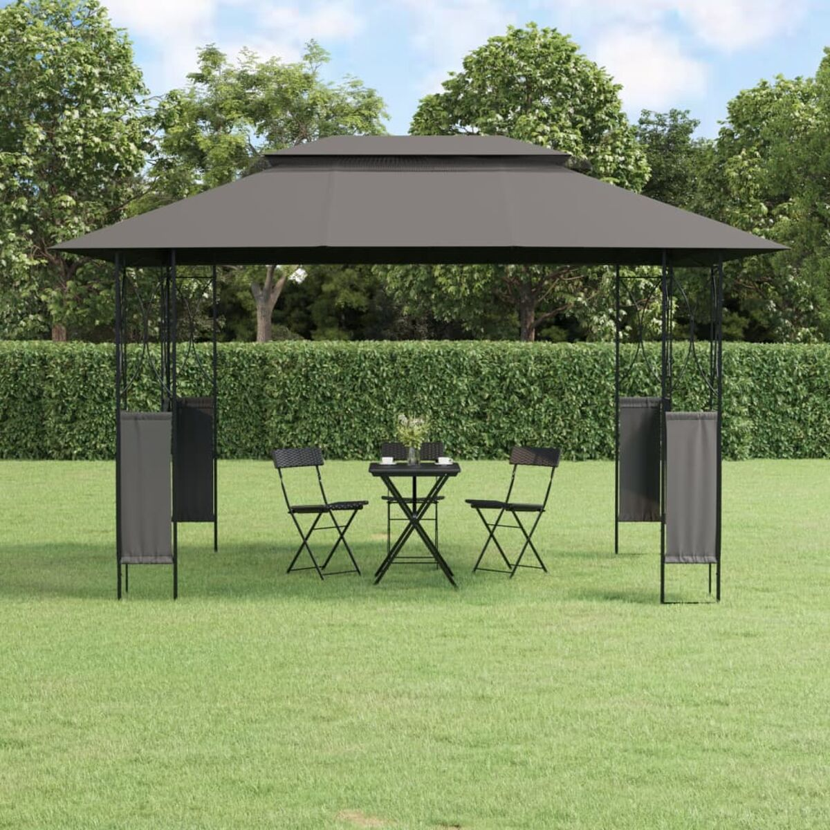 Pavillon in einer Wiese. Schwarzer Metallrahmen, graues Dach und zwei Stühle. Grüne Hecke umgibt.