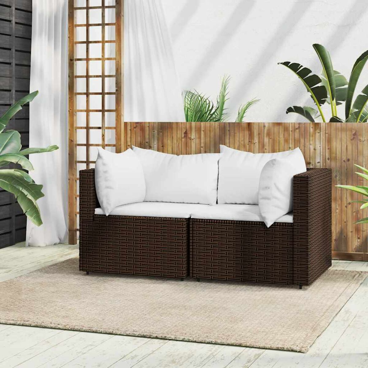 Braunes Outdoor-Sofa aus Korbgeflecht mit weißen Kissen. Hintergrund: Holzwand.