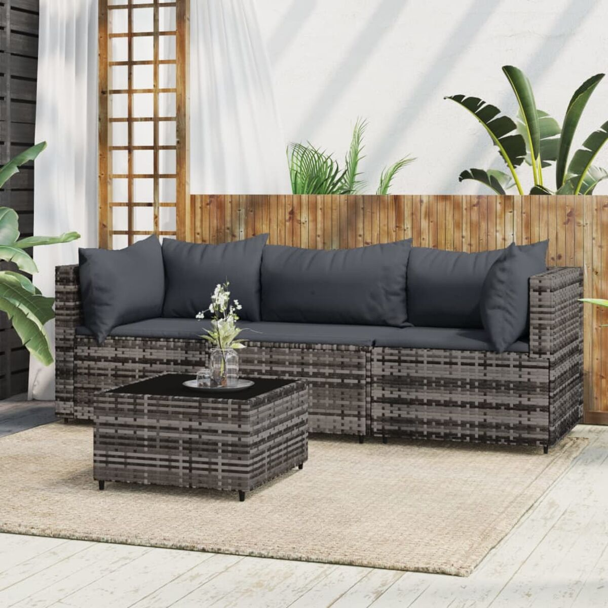 Geflochtenes Outdoor-Sofaset mit grauen Kissen und Couchtisch auf Terrasse.
