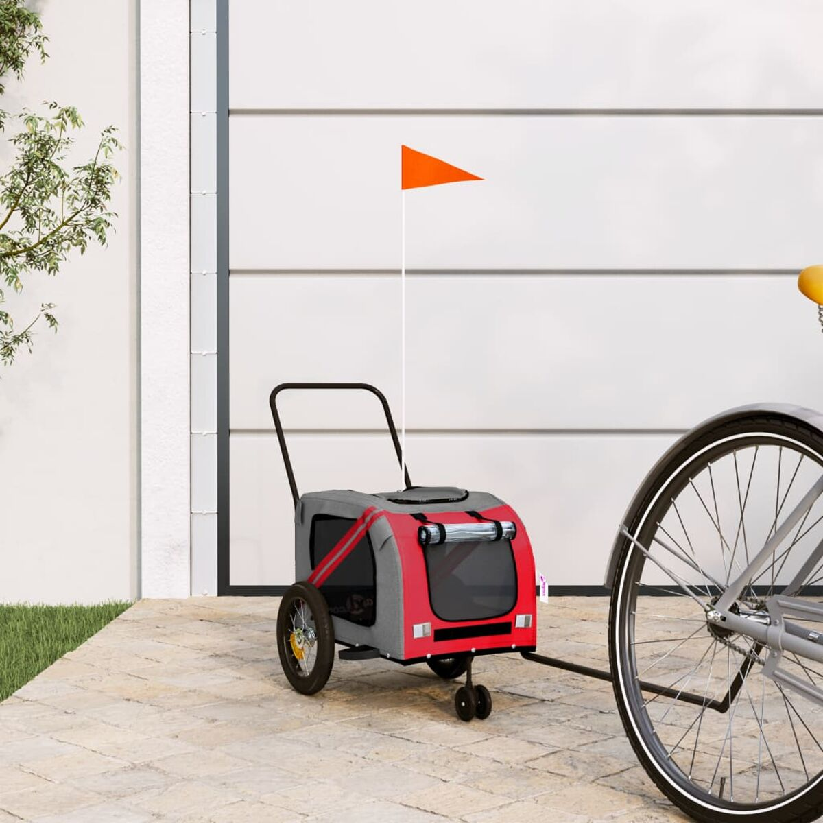 Roter und grauer Haustieranhänger am Fahrrad. Orange Fahne oben.