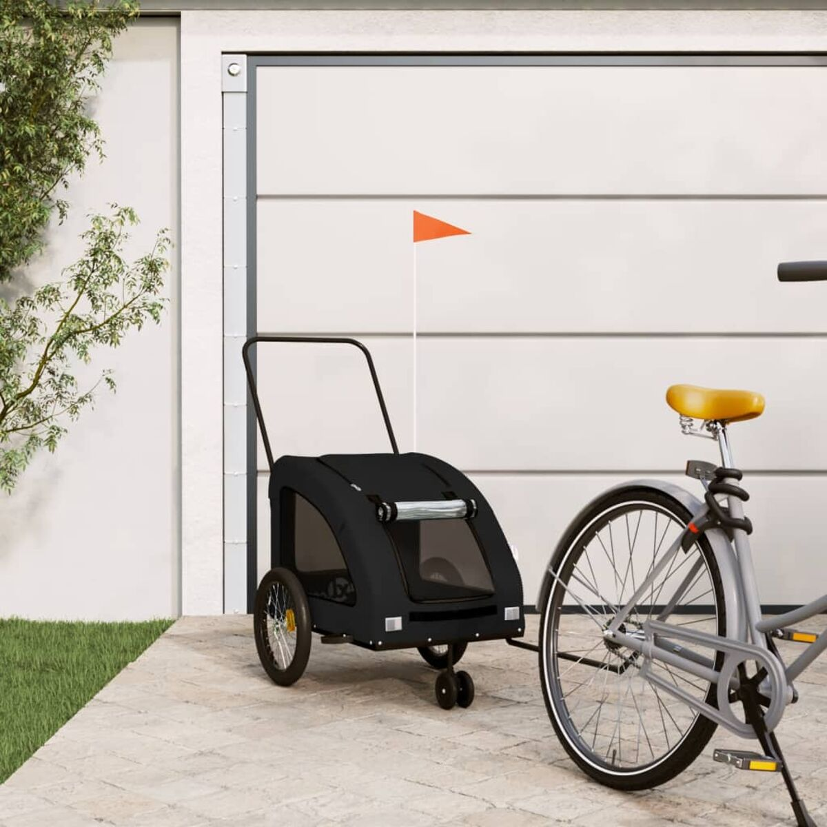 Ein schwarzer Tieranhänger, der an einem Fahrrad befestigt ist. Am Anhänger ist eine orangefarbene Fahne.