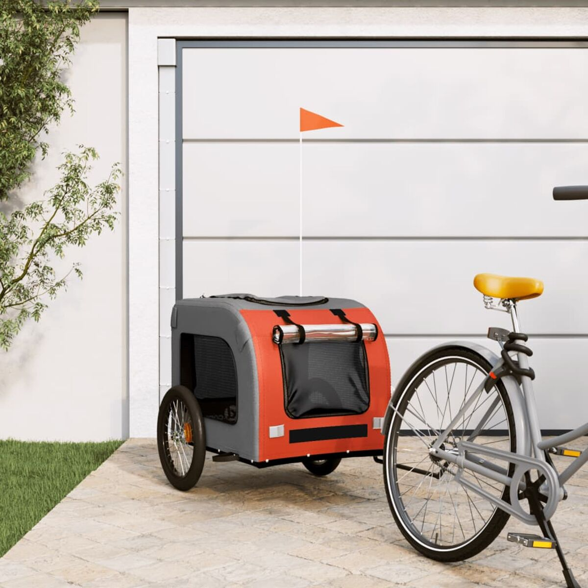 Haustieranhänger an einem Fahrrad befestigt. Der Anhänger ist orange und grau mit Fahne.