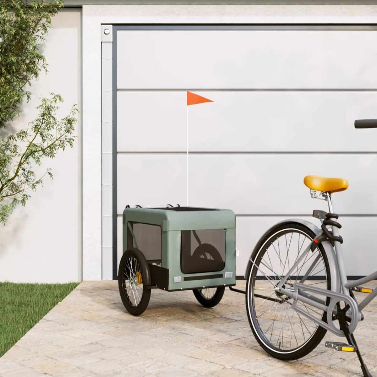 Fahrrad mit Anhänger. Der Anhänger ist grün mit einer kleinen orangefarbenen Fahne.