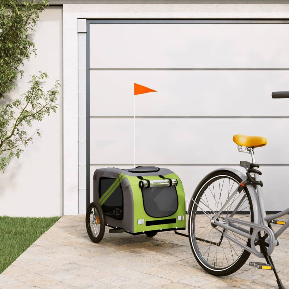 Grüner und grauer Haustieranhänger an einem grauen Fahrrad. Eine orangefarbene Flagge ist befestigt.