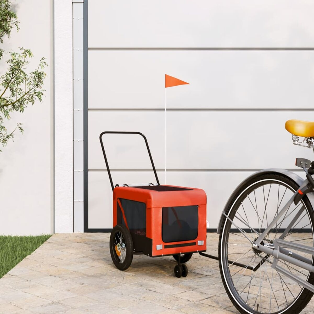 Roter und schwarzer Haustieranhänger mit orangefarbener Fahne. Fahrrad rechts sichtbar. Weiße Tür.