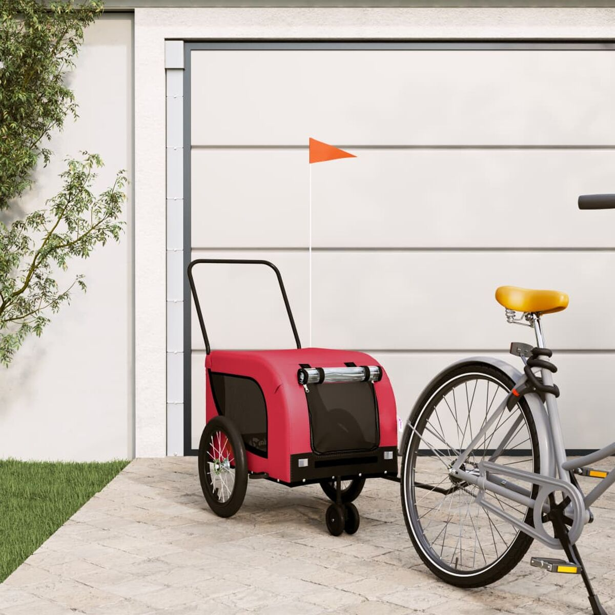 Ein roter Hundeanhänger an einem Fahrrad mit orangefarbener Flagge, geparkt vor einer weißen Garage.