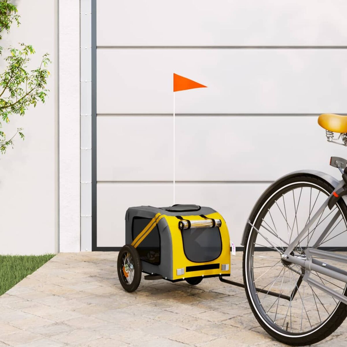 Gelber und grauer Haustier-Fahrradanhänger mit orangefarbener Fahne, an einem Fahrrad befestigt.