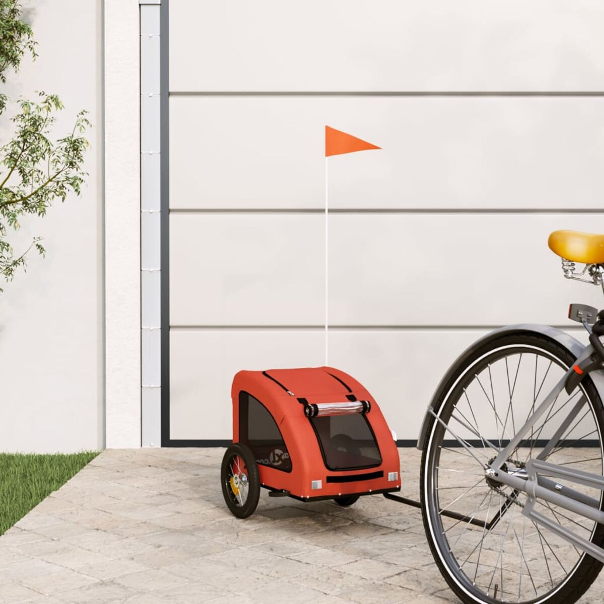 Roter Fahrradanhänger mit orangefarbener Fahne, an einem Fahrrad. Auf Pflasterfläche.