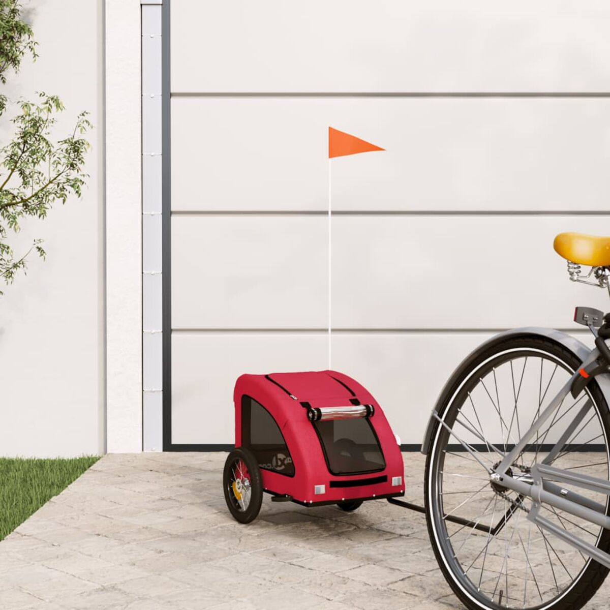 Roter Fahrradanhänger mit orangefarbener Fahne, geparkt neben einem Fahrrad.