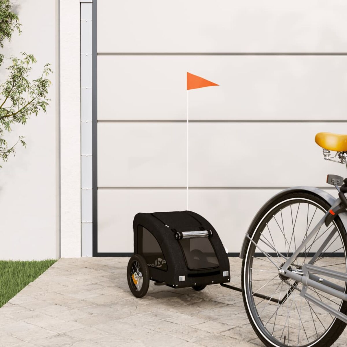Schwarzer Tieranhänger an einem Fahrrad befestigt, mit orangefarbener Flagge, geparkt auf einer gepflasterten Oberfläche.