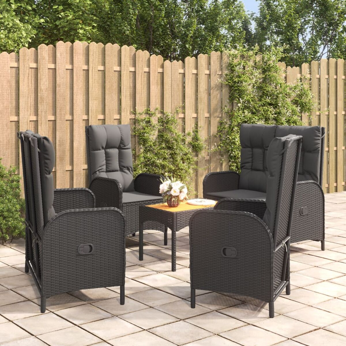 Eine Terrasse mit vier grauen Korbstühlen und einem kleinen Tisch, dahinter ein Holzzaun.