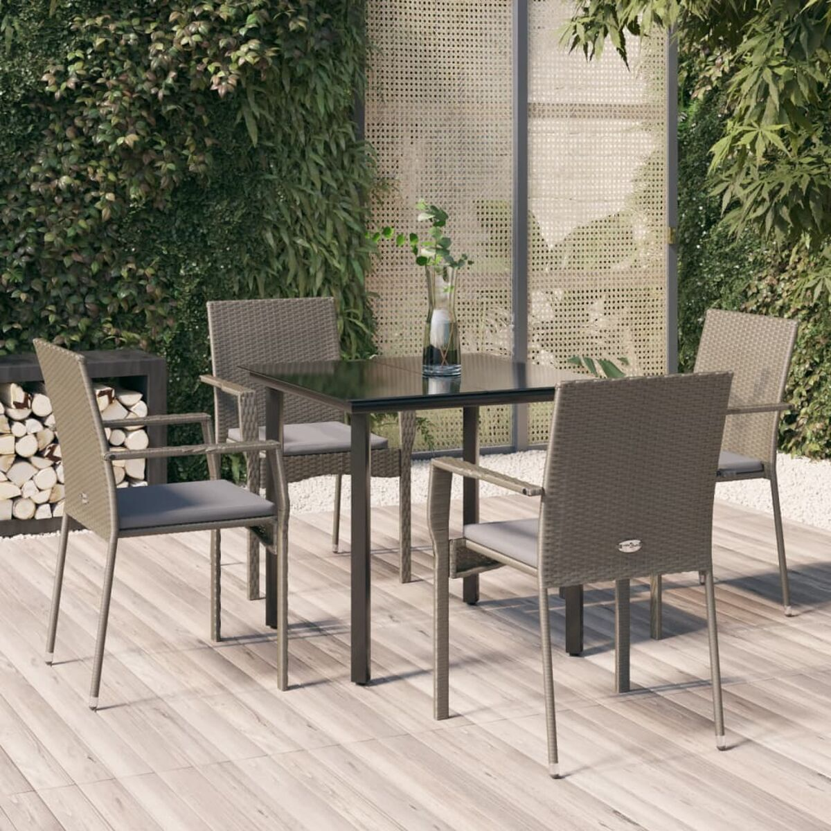 Ein Tisch für vier Personen mit Rattanstühlen, einem quadratischen Tisch und einer Vase.