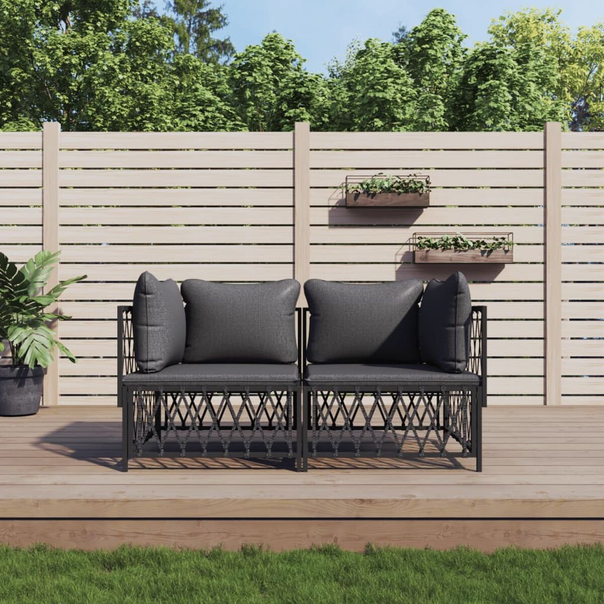Zwei schwarze Rattan-Stühle mit grauen Kissen auf einem Holzdeck, mit Holzzaun im Hintergrund.