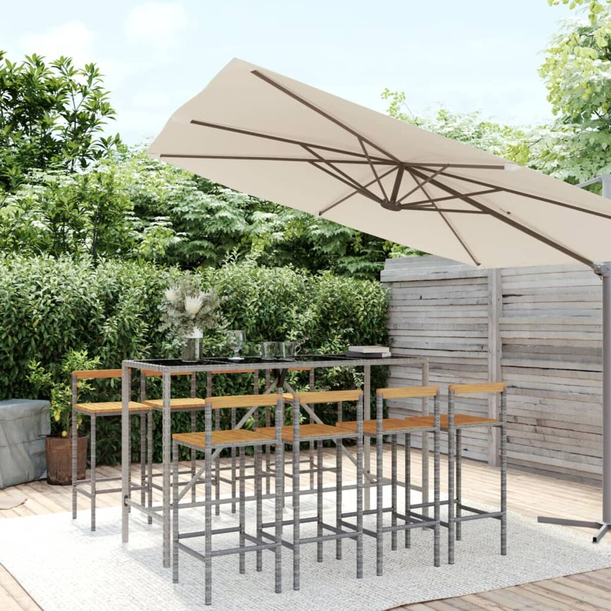 Outdoor-Bar-Set mit rechteckigem Tisch, sechs Hockern und einem großen Sonnenschirm über einer Terrasse.