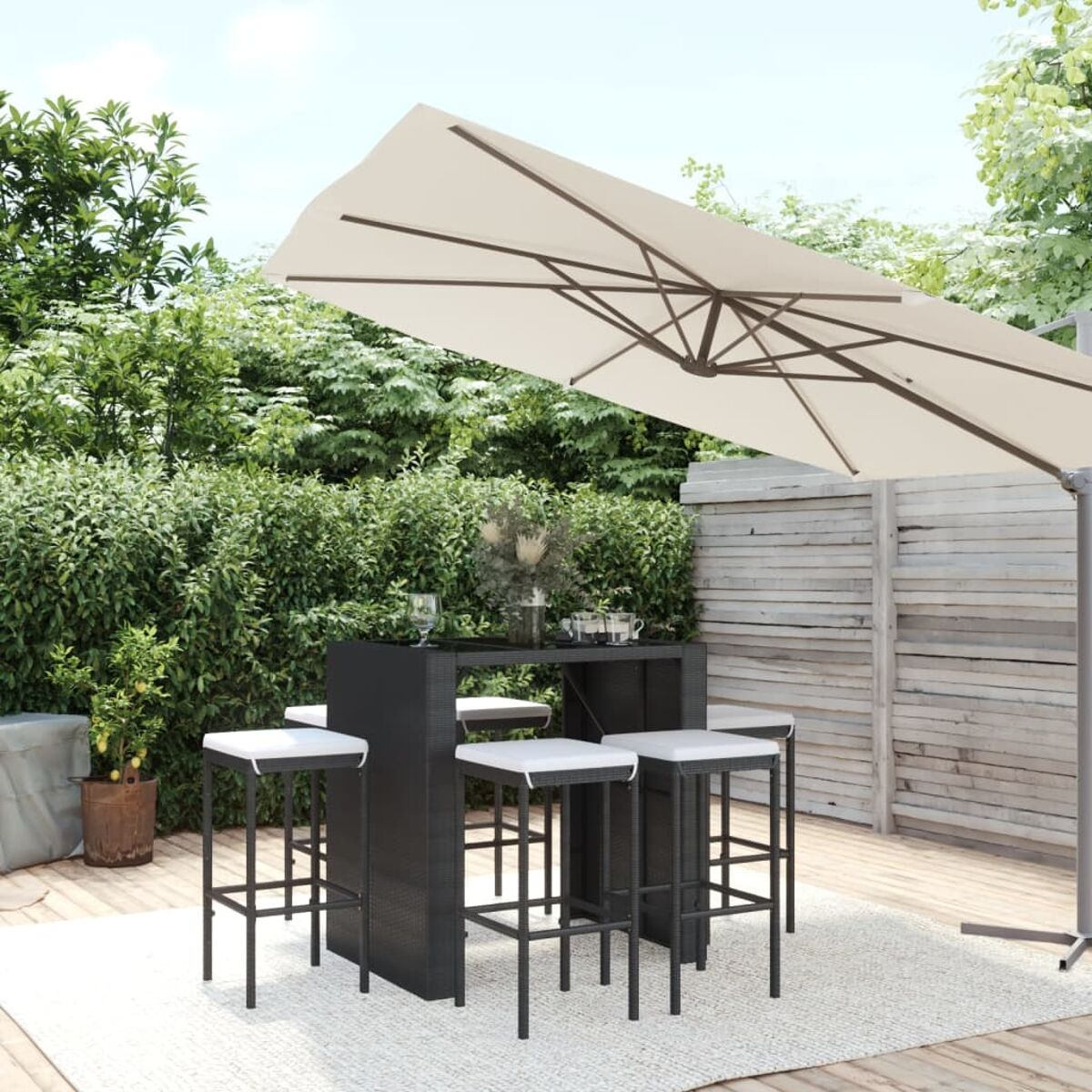 Garten-Essgruppe mit Bartisch, Hockern, Sonnenschirm und Grün im Hintergrund.
