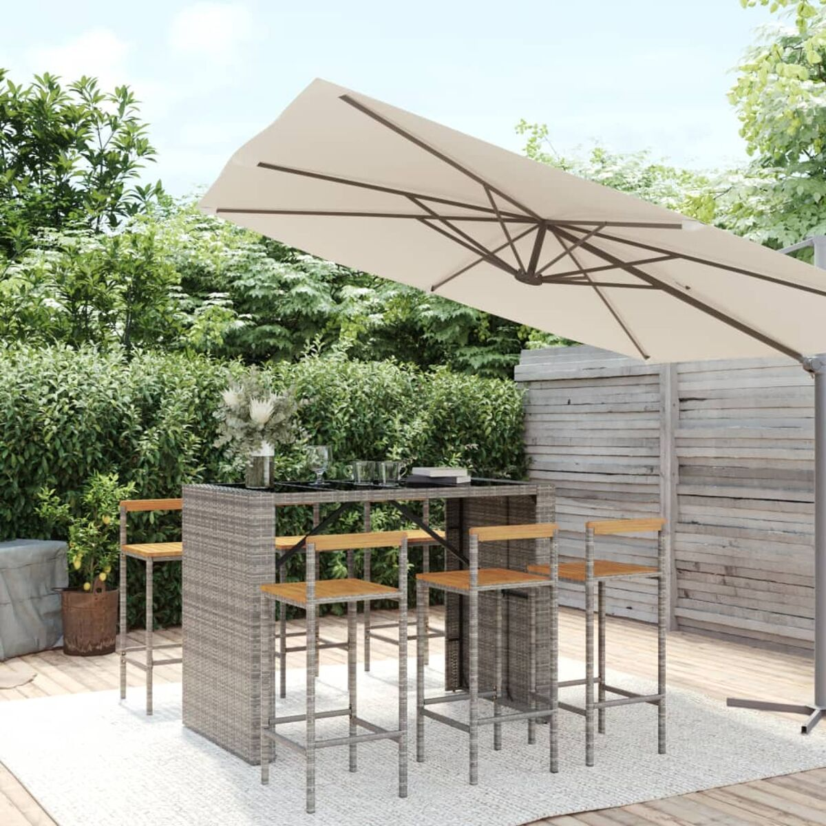 Ein Terrassenset mit Tisch und Stühlen. Es gibt einen großen Schirm. Die Möbel sind grau.