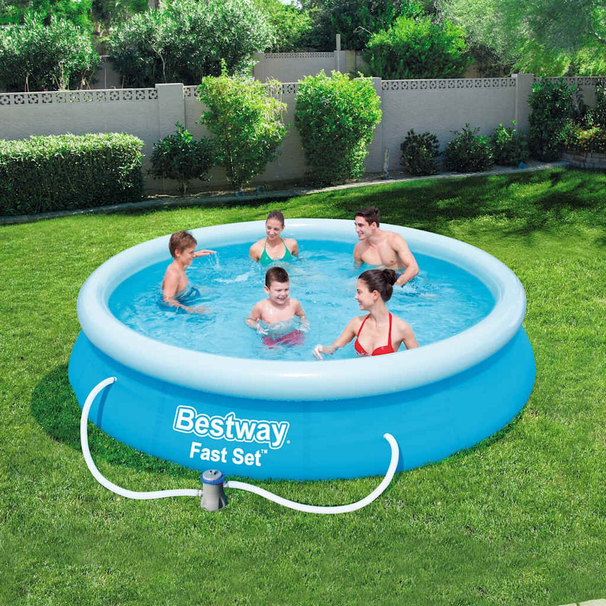 Fünf Personen in einem blauen Aufstellpool. Eine Pumpe ist angeschlossen. Grünes Gras umgibt den Pool.