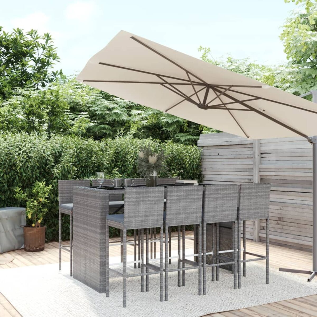 Garten-Bar-Set mit weißem Sonnenschirm, Tisch und Hockern auf einem Teppich.