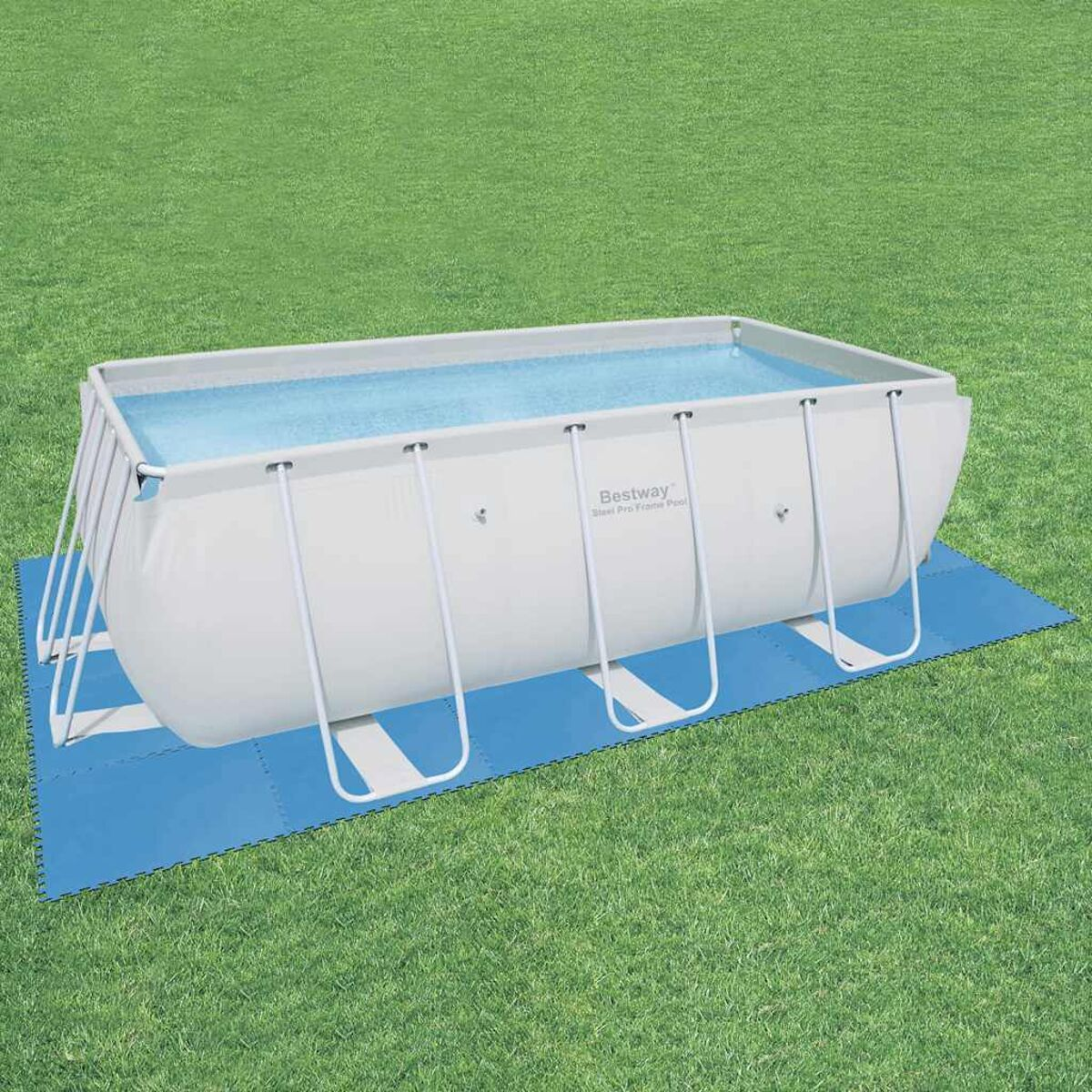 Ein rechteckiger Aufstellpool, weißer Rahmen, blaue Matte. Er steht auf Gras.