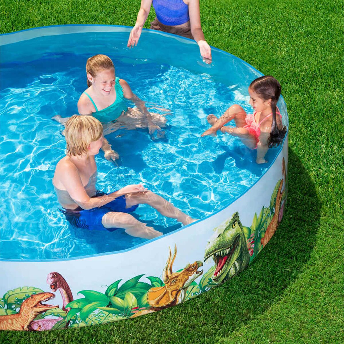 Kinder in einem Pool mit Dinosaurier-Motiv. Grünes Gras um den Pool herum.