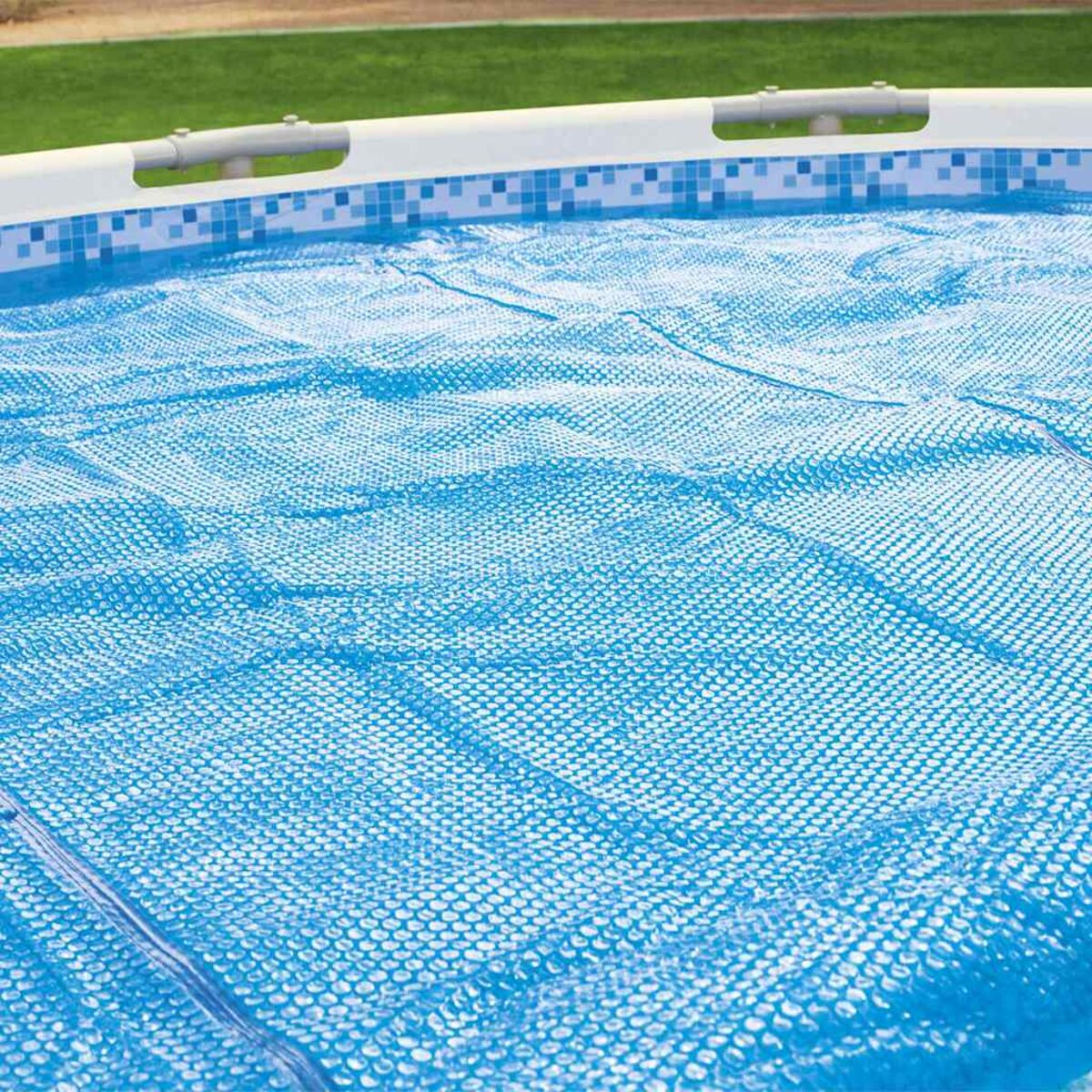 Nahaufnahme einer blauen, mit Blasen bedeckten Poolabdeckung auf einem Pool, mit Rasen im Hintergrund.