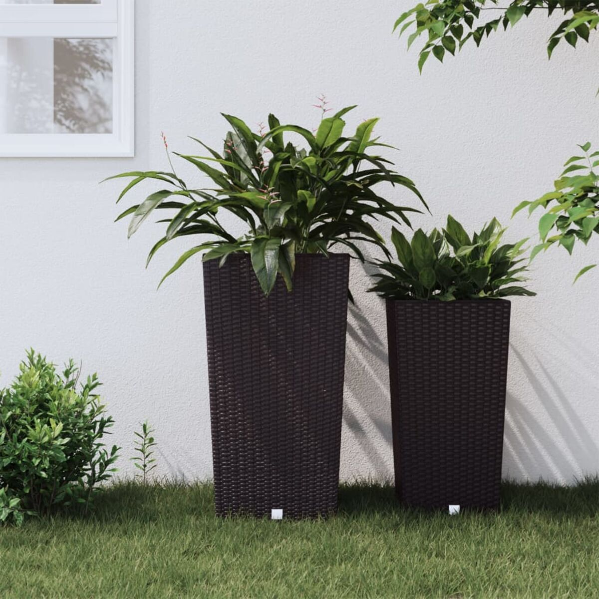 Zwei braune, gewebte Pflanzgefäße mit grünen Pflanzen auf Gras.