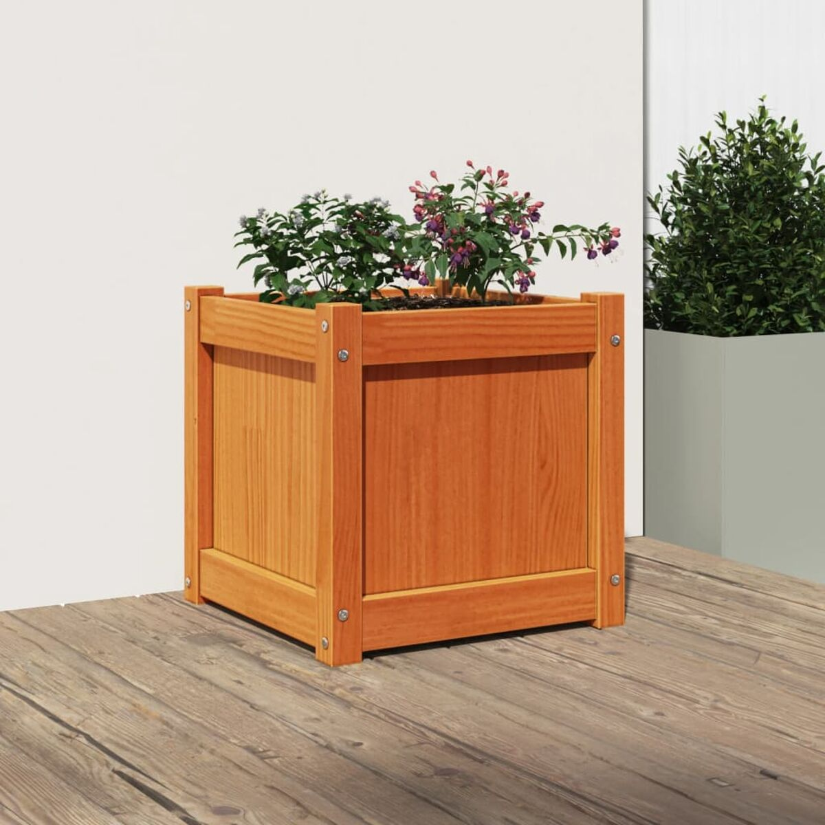 Eine hölzerne Pflanzkasten mit bunten Blumen, auf einem Holzdeck. Grüner Pflanze im Hintergrund.
