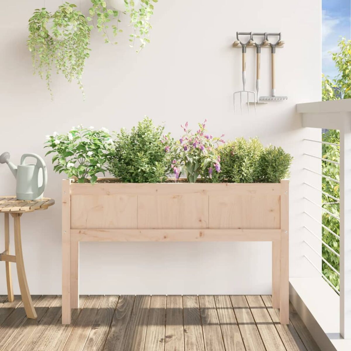 Holz-Pflanzkasten mit Pflanzen auf Holzterrasse, weiße Wand, Garten im Hintergrund.