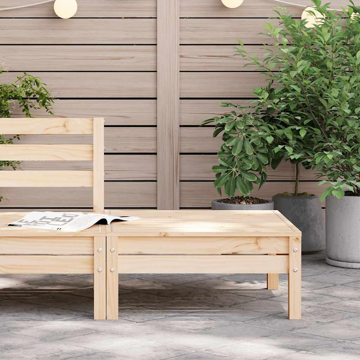 Panca da esterno in legno con un libro sopra. Sfondo: una staccionata in legno e piante in vaso.