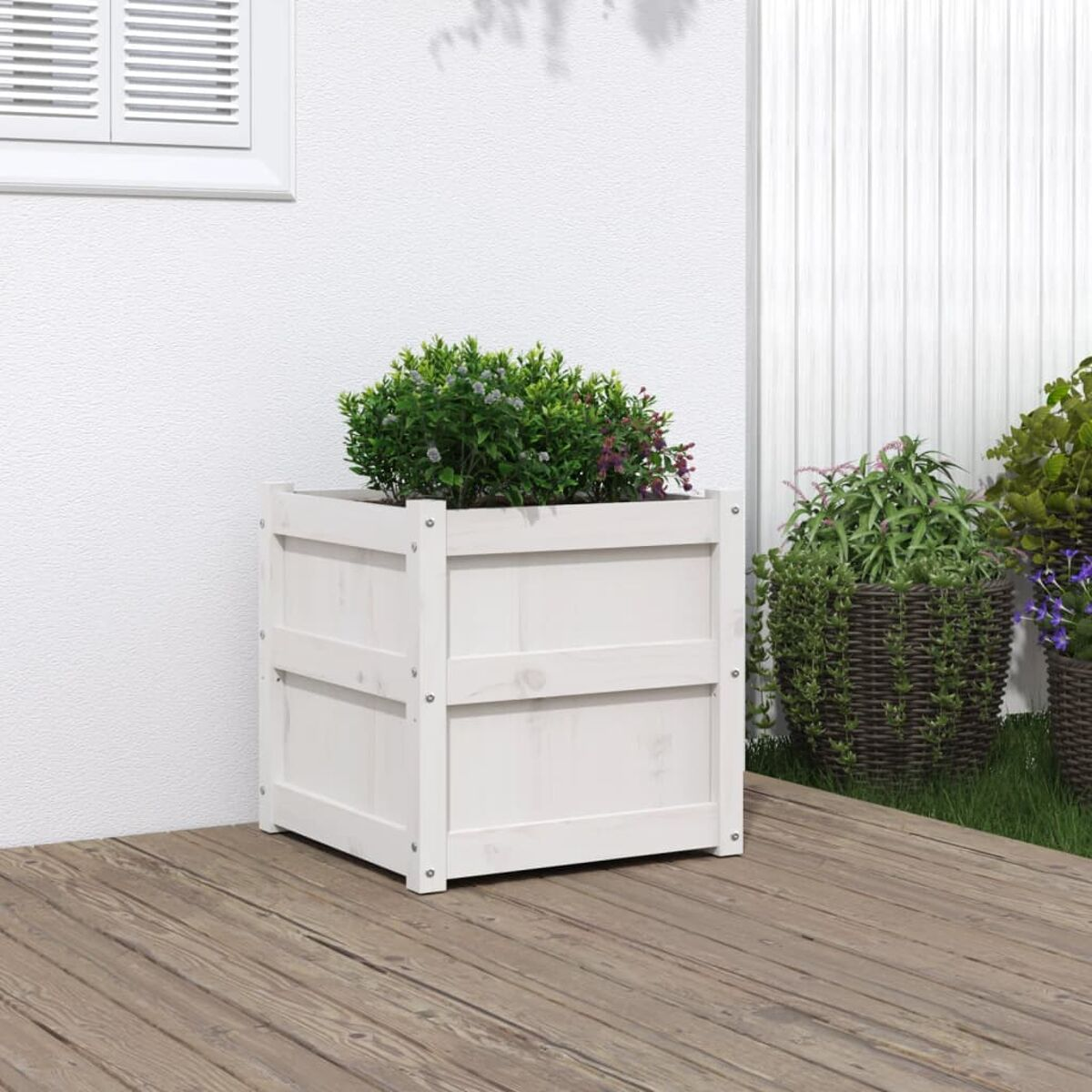Weißer Holzpflanzer mit grünen Pflanzen. Quadratische Form, auf Holzdeck platziert.