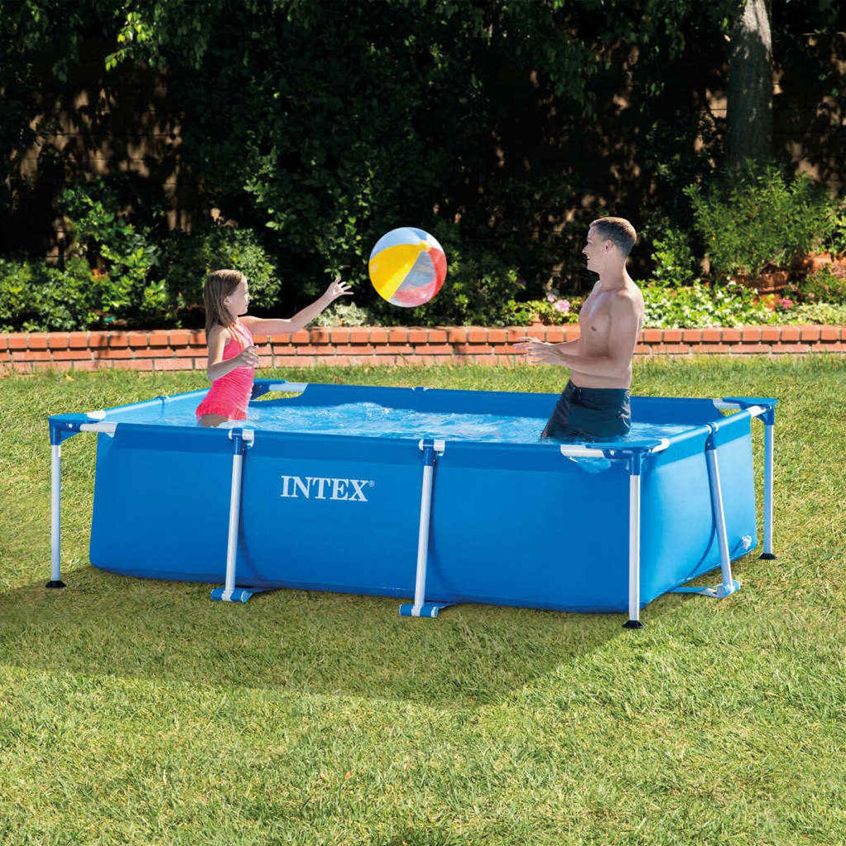 Menschen spielen in einem rechteckigen blauen Intex-Pool im Garten.