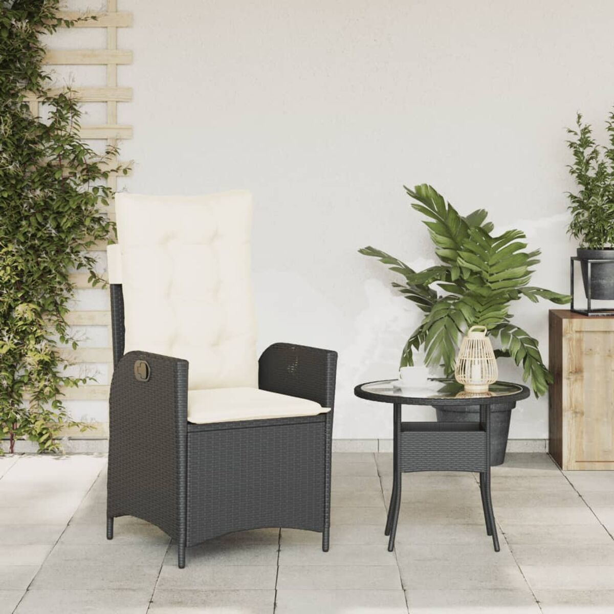 Ein schwarzer Korbstuhl mit cremefarbenem Kissen, ein kleiner Tisch und eine Pflanze auf einer Terrasse.