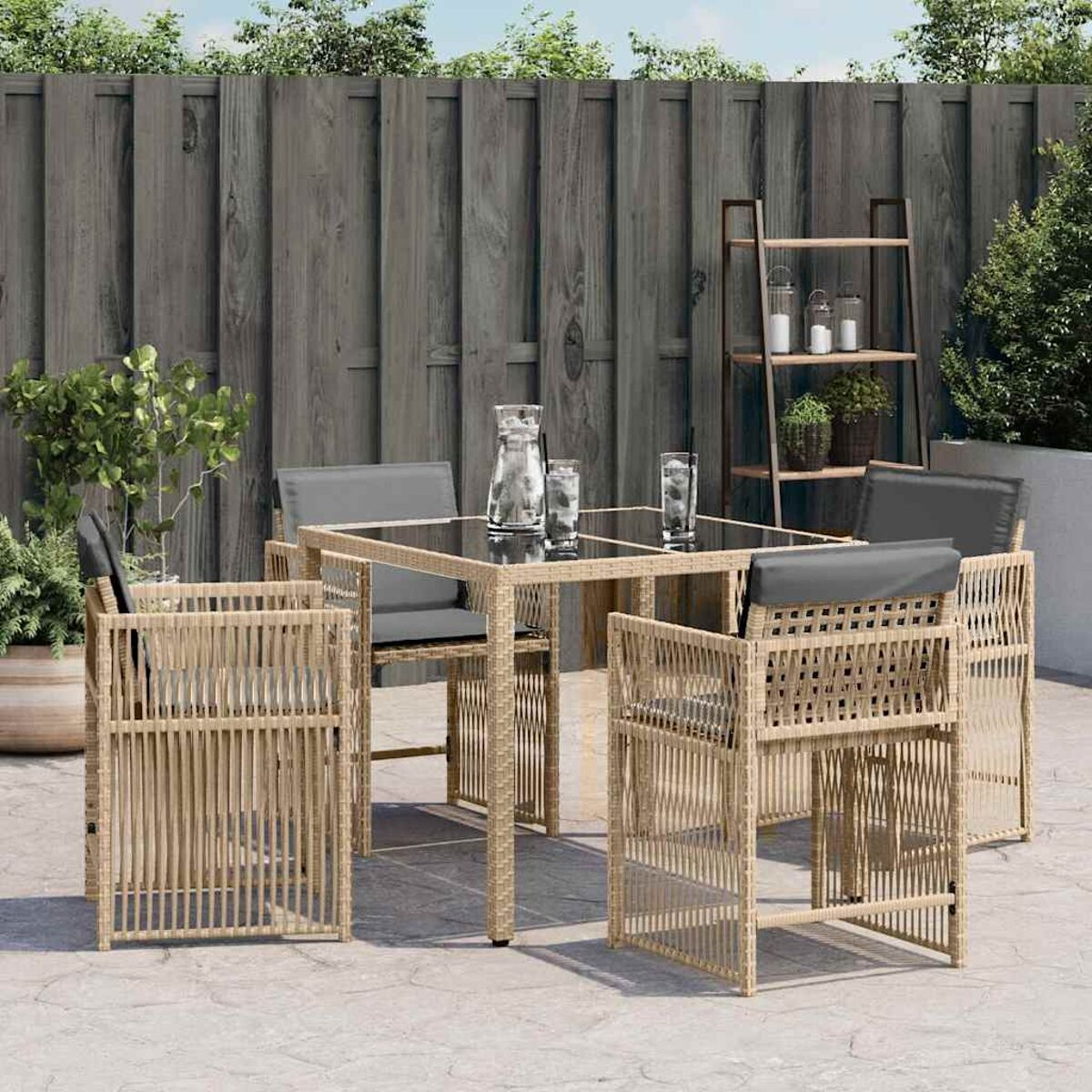 Un set da pranzo all'aperto con sedie in vimini, un tavolo con piano in vetro e accessori su un patio.