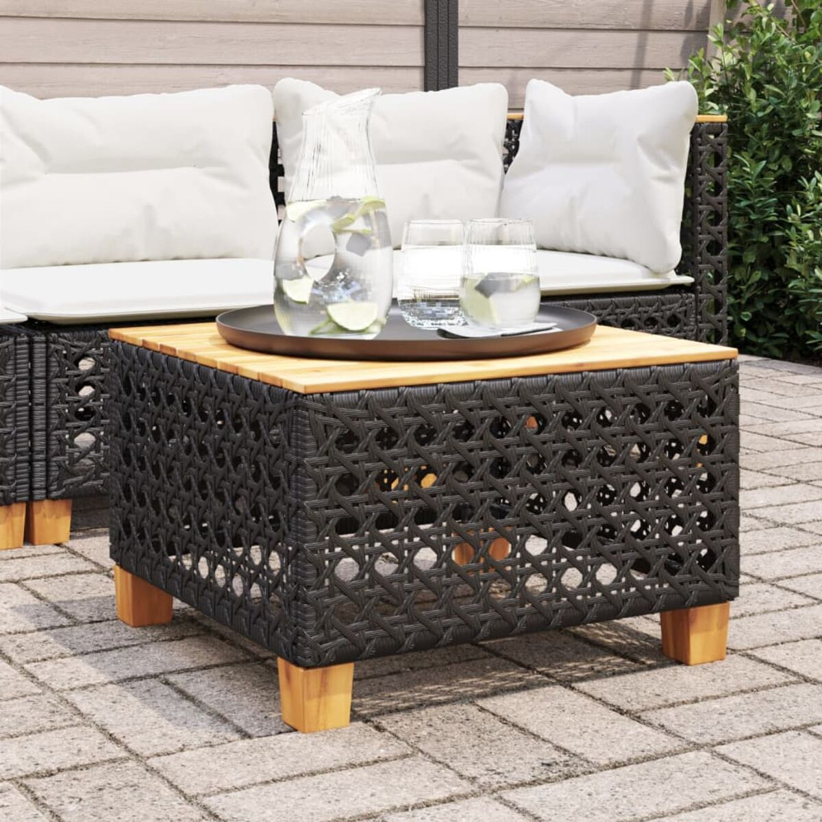 Outdoortisch mit gewebtem schwarzen Gestell und Holzplatte. Getränke und Tablett darauf.