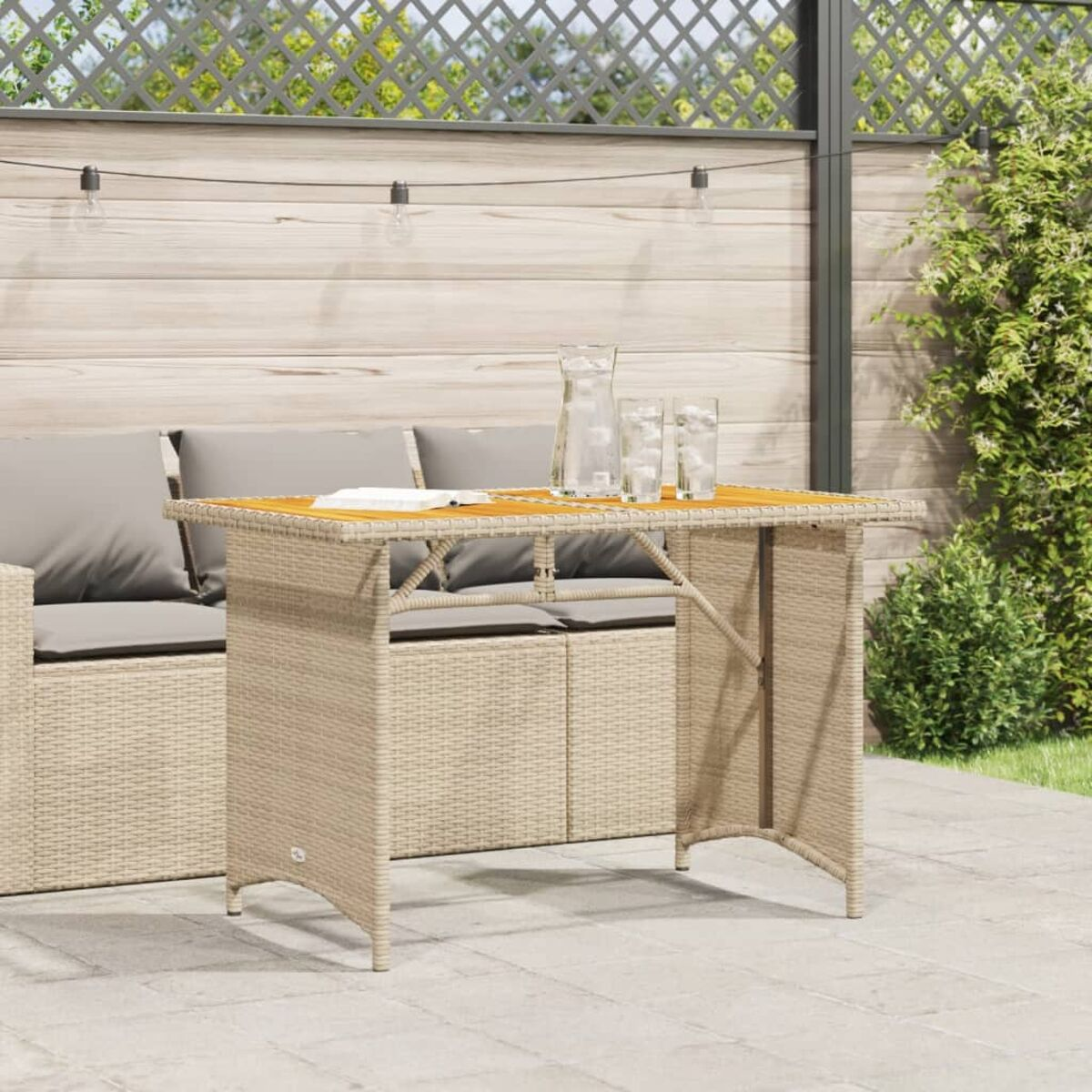Rattan-Tisch im Freien mit Glas und Gläsern. Holzplatte. Hellbeige Farbe.