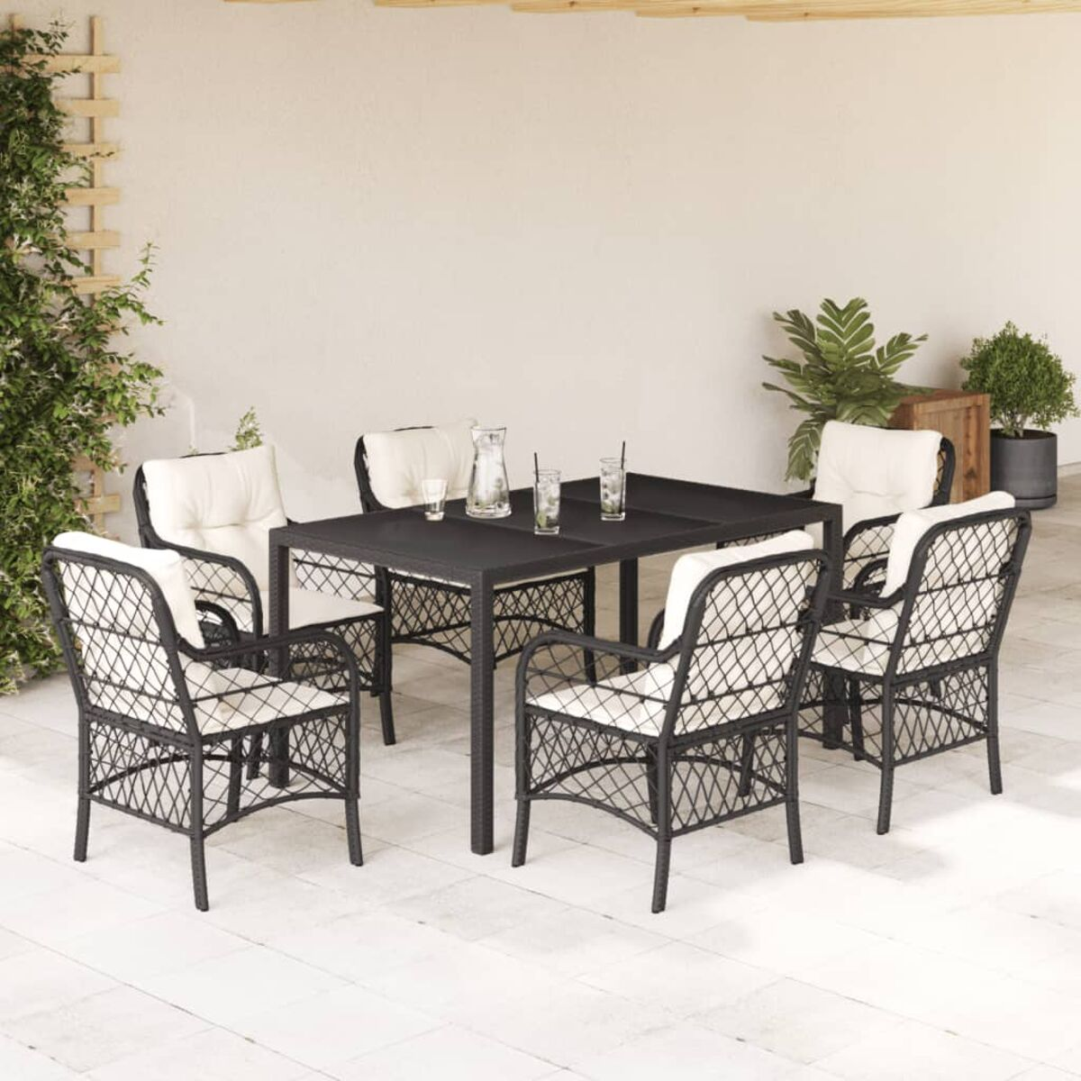 Essgruppe im Freien mit schwarzen Korbstühlen, Tisch und Getränken, auf einer Terrasse.